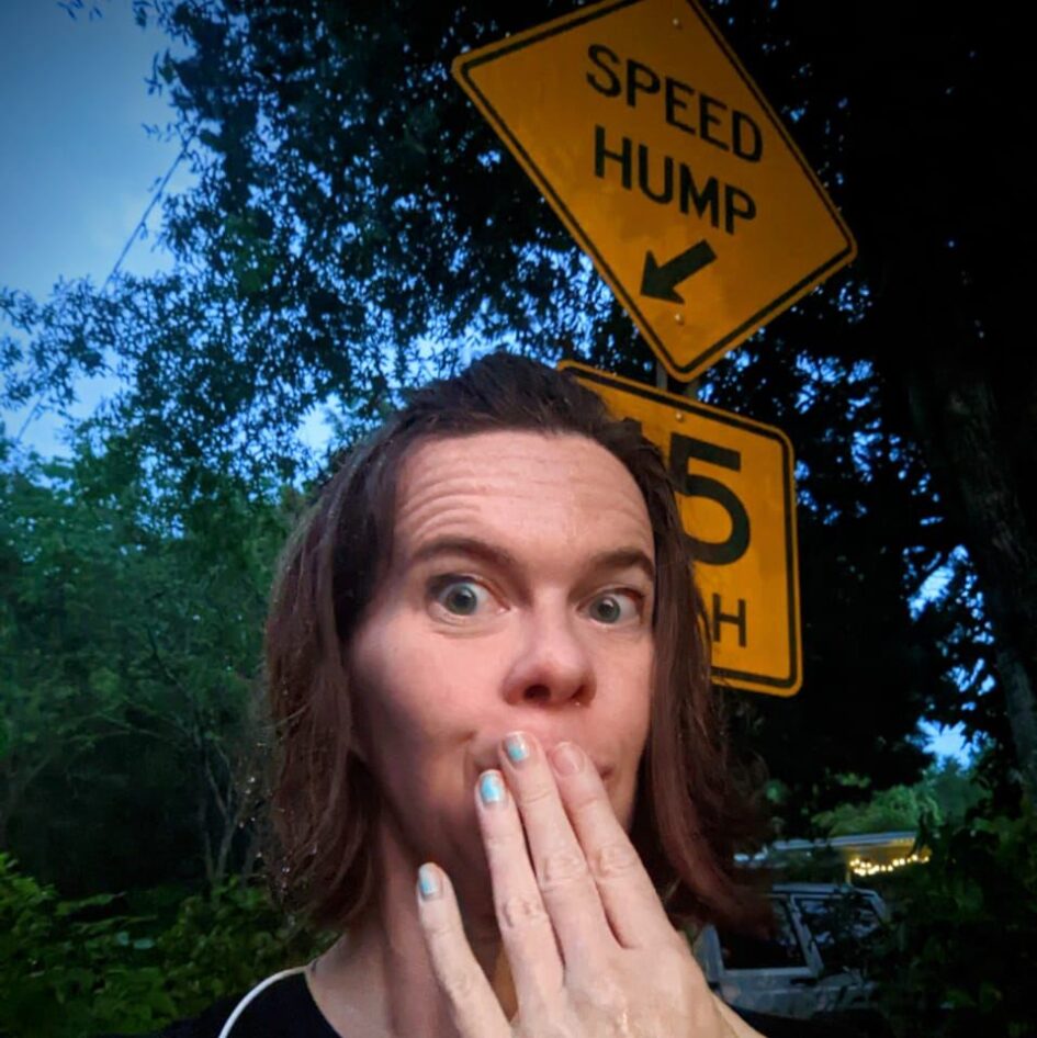 a person is making a face in front of a street sign that says speed hump