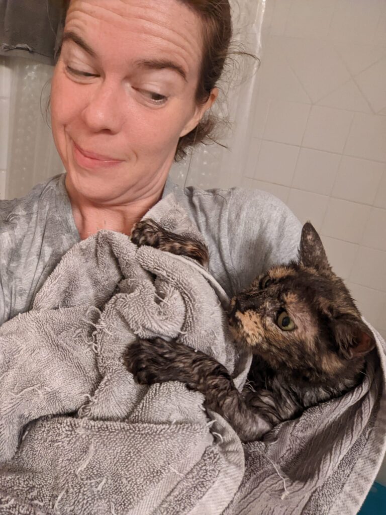 a person is looking defensive and carefully holding a cat wrapped in a towel
