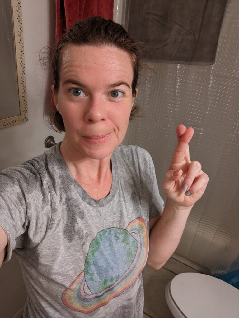 a person is crossing their fingers and looking wet in a bathroom