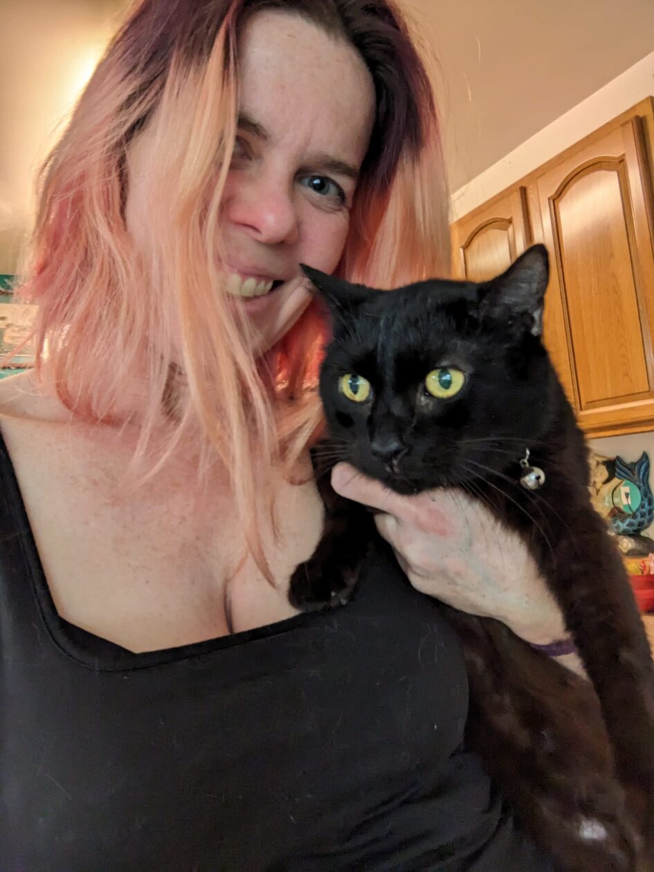 a person is trying to hold a black cat and take a selfie and the cat is looking distressed