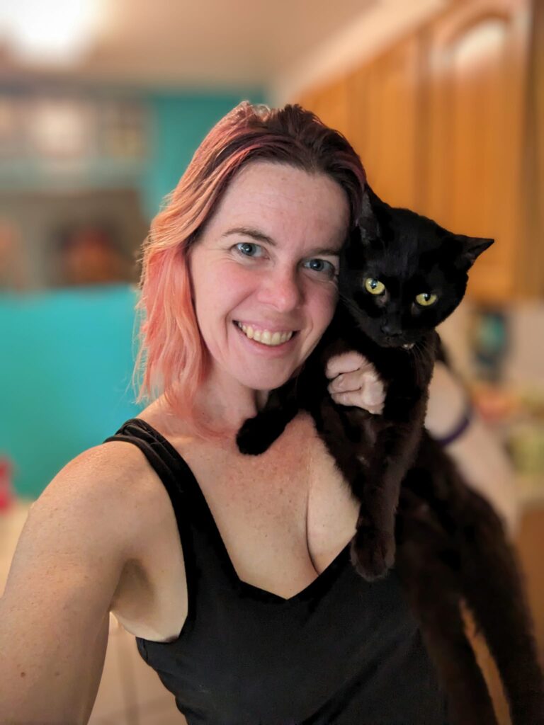 a person is trying to hold a black cat and take a selfie and it is looking very annoyed
