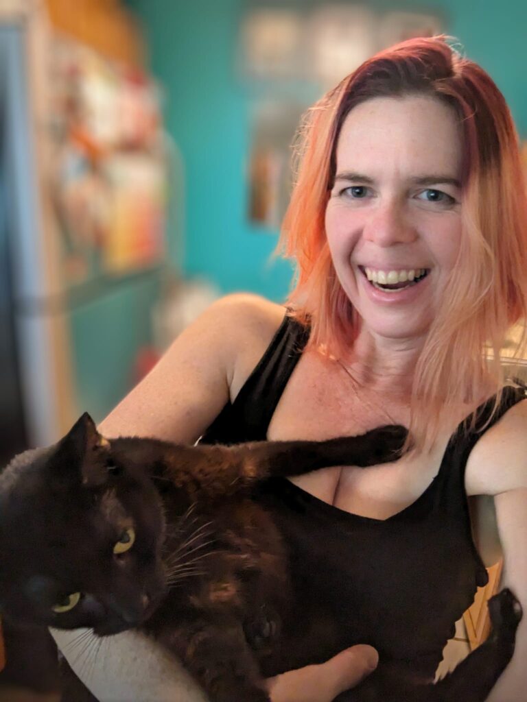 a person is trying to hold a black cat and take a selfie but it is pushing away from her