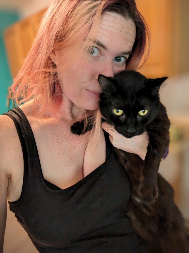 a person is trying to hold a black cat and take a selfie