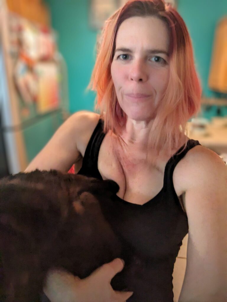 selfie of a person trying to hold a black cat that is jumping