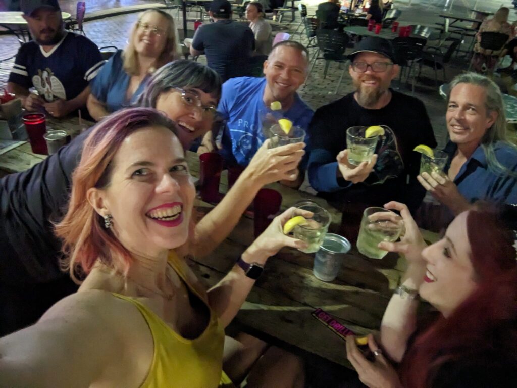 a group of people at a picnic table are holding up shot glasses with lemons on the rim