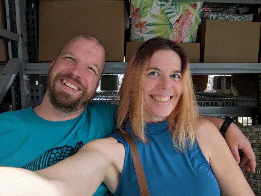 selfie of two smiling people sitting in a furniture store of some kind
