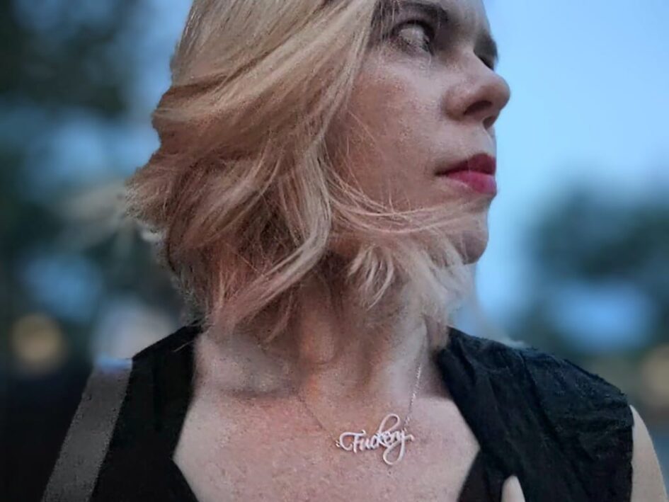 dramatic selfie of a person wearing lipstick and a black dress and a necklace that says fuckery