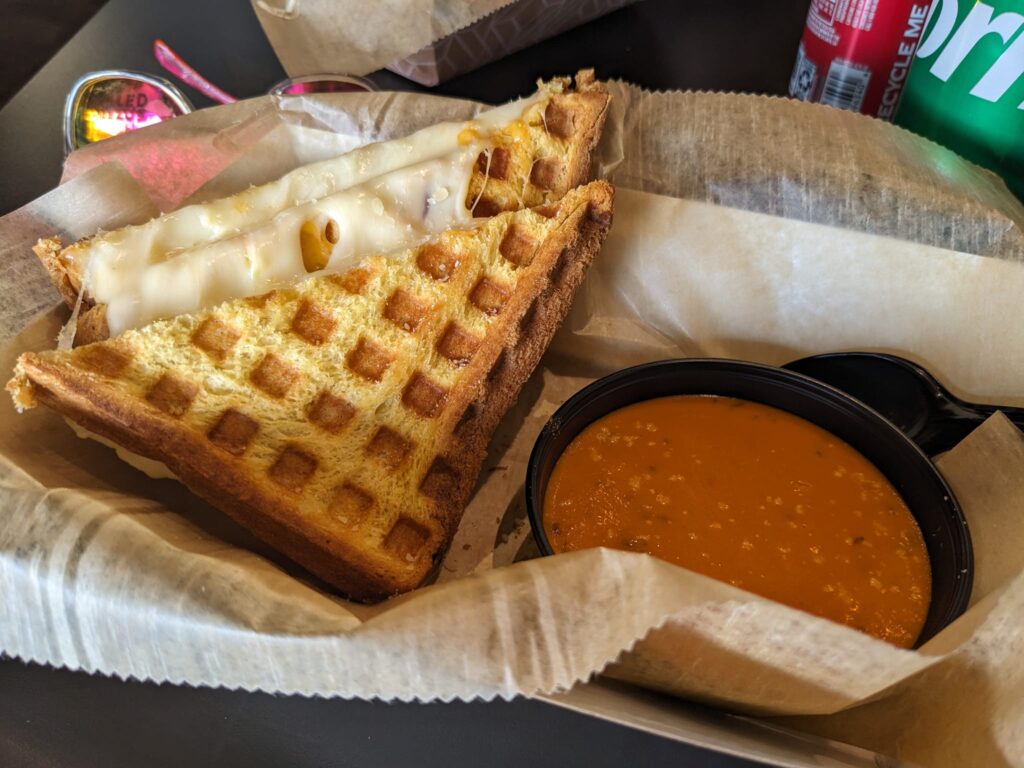 a grilled cheese sandwich next to a bowl of soup