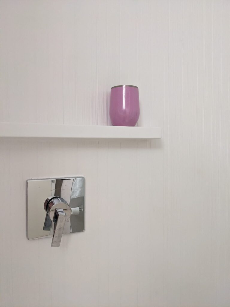 a pink cup is sitting on a ledge in a hotel shower
