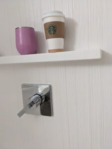 a pink cup and a to-go coffee cup on a ledge in a hotel shower