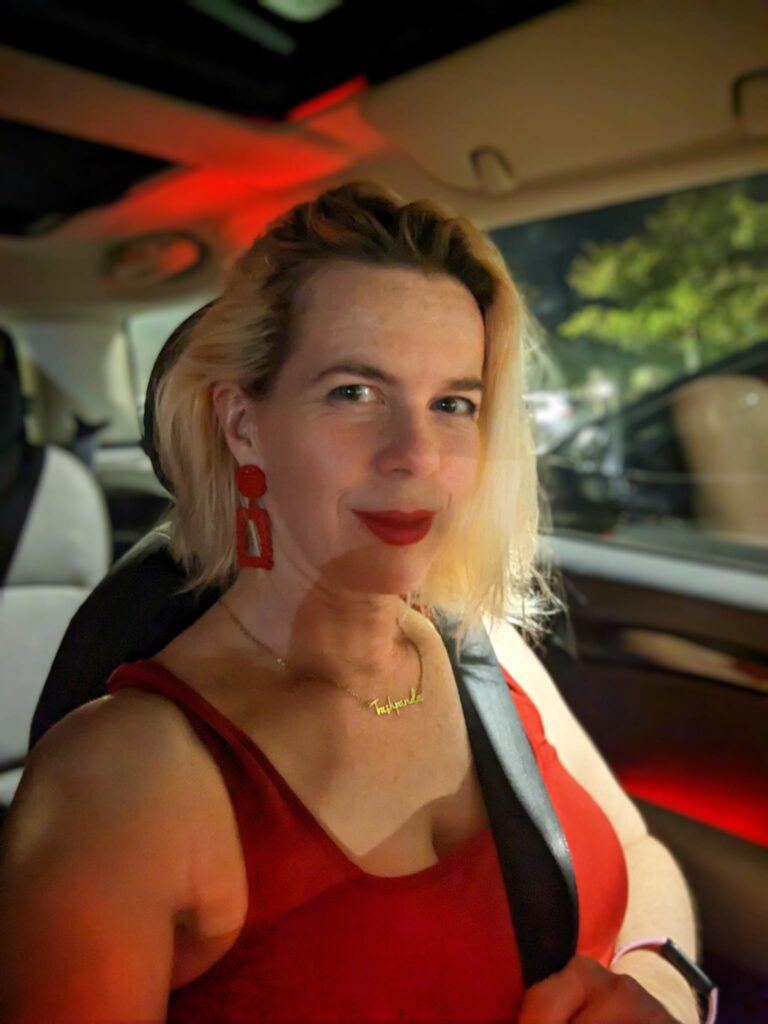 selfie of a person in a car wearing a red dress and lipstick