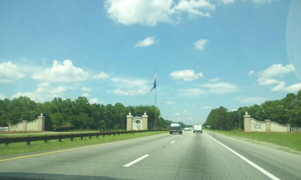a highway shoots between a symbolic wall with a flag and the palm tree symbol for South Carolina