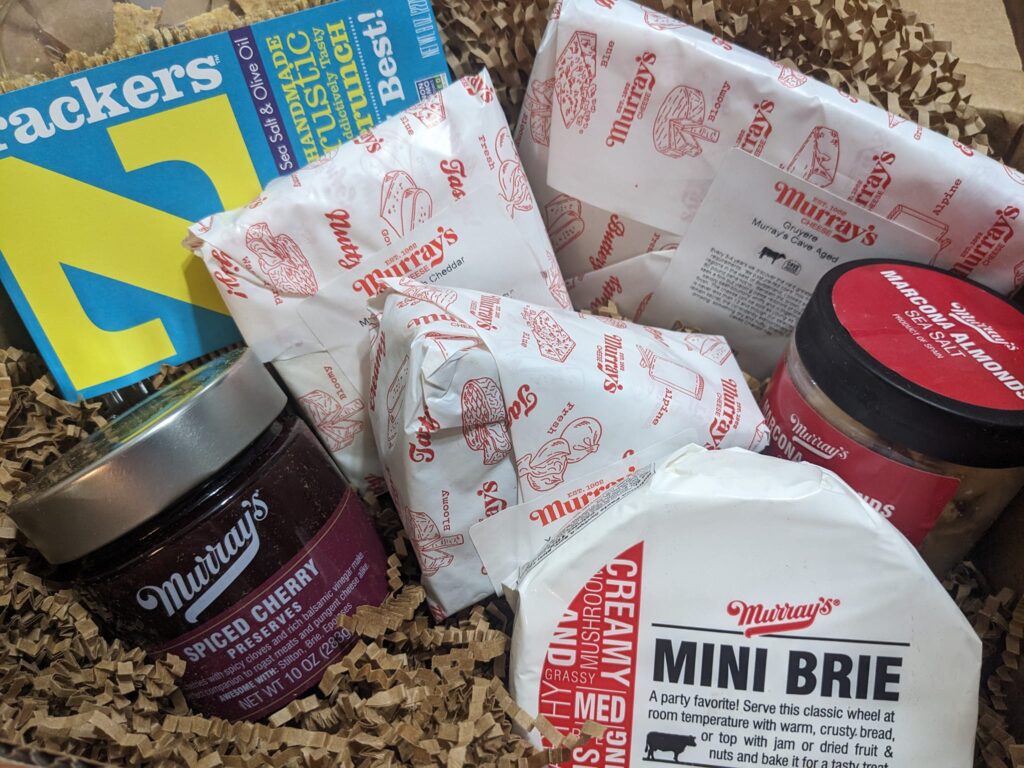 a box of assorted types of cheese in deli wrappers