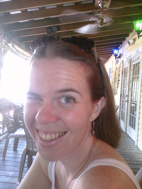 a blurry picture of a person smiling for the camera on a patio of some kind