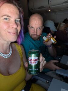 two people are seated in an airplane holding drinks