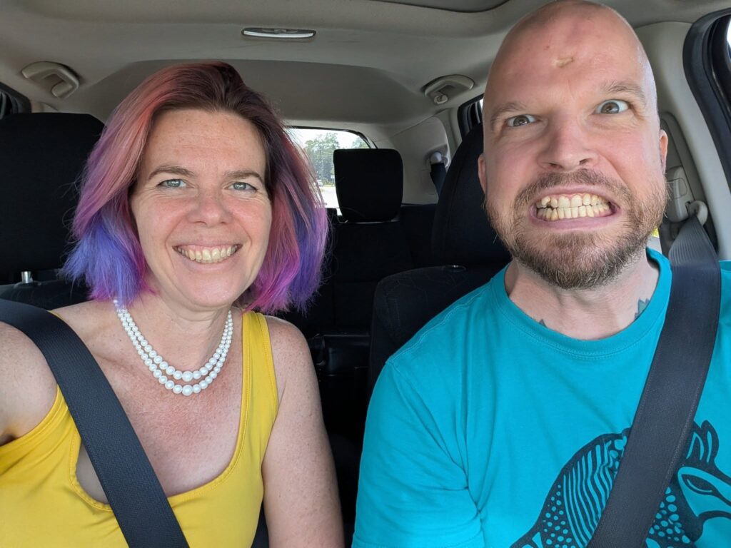selfie of two people wearing seat belts in a car