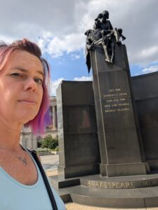 a person is looking skeptical in front of a large memorial to Shakespeare in black marble