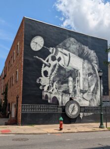 the side of a building has a mural of power tools on one side intersecting with a lion face on the other side