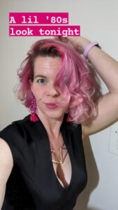 selfie of a person with short pink hair posing dramatically and making a face with the text 'a lil 80s look tonight'