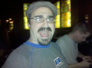 a person in a dark pub is making a face and brightly illuminated by a flash