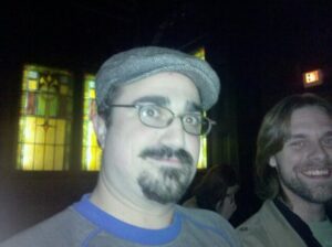 two men in a dark pub are caught by a bright camera flash