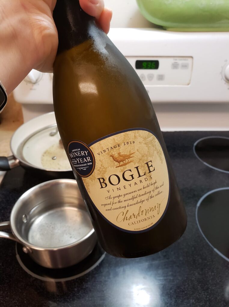 a hand is holding up a bottle of Bogle wine and in the background is a stove with pots on it