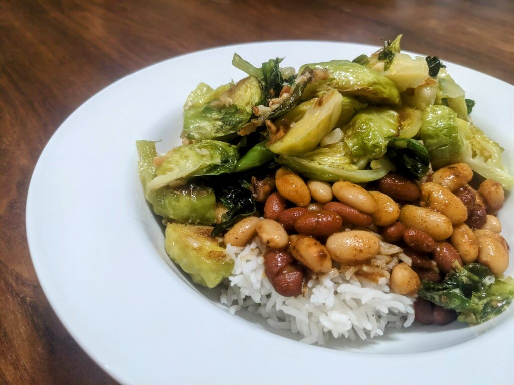 a plat has beans and rice and sauteed brussels sprouts