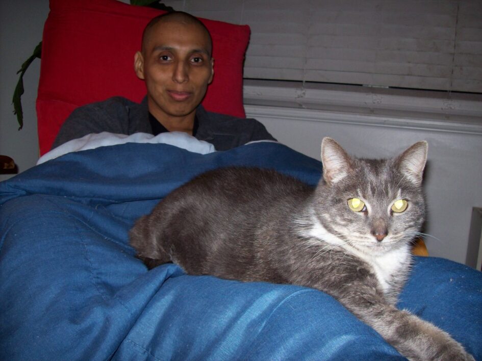 a person is sitting in a chair with a fluffy blanket over themselves and a cat is sprawled in their lap