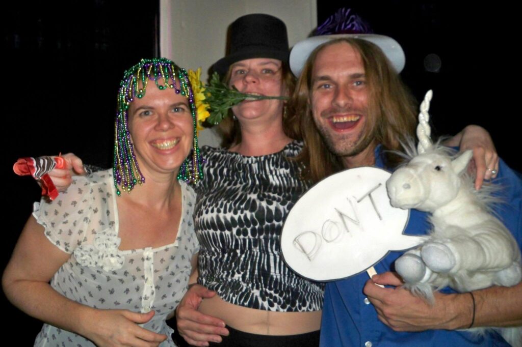 three people posing for a photo wearing an assortment of hats and holding props like they are at a photo booth